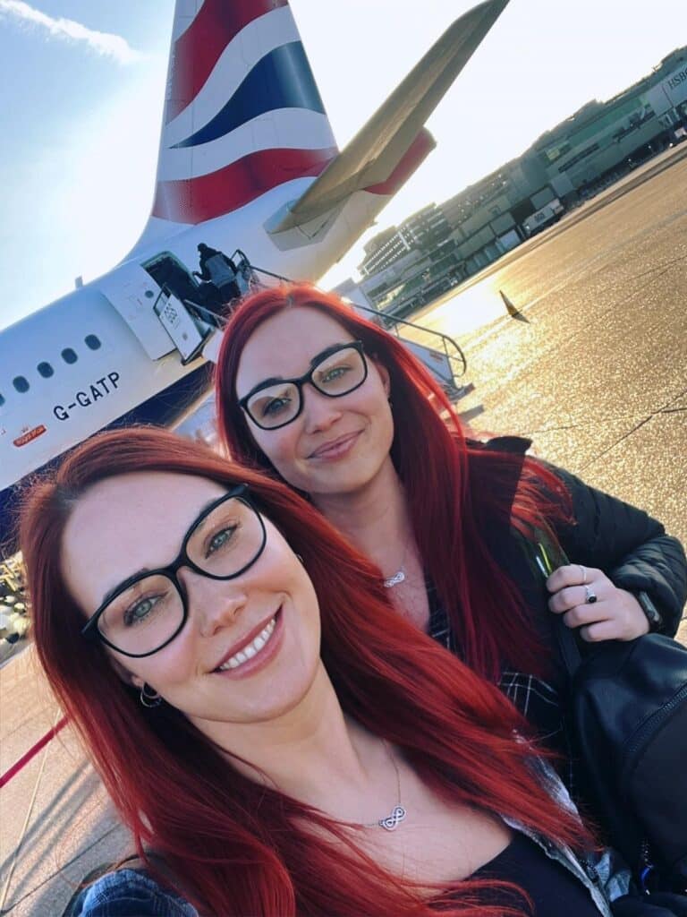 Two women with red hair and black glasses take a selfie in front of a plane!