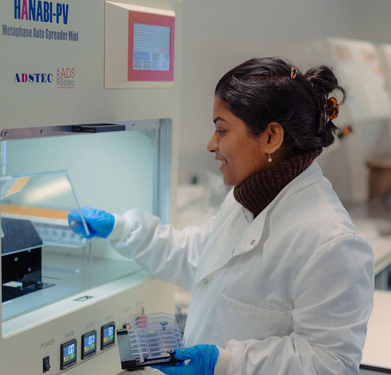 A woman in lab coat using a machine in the Rare Disease Lab