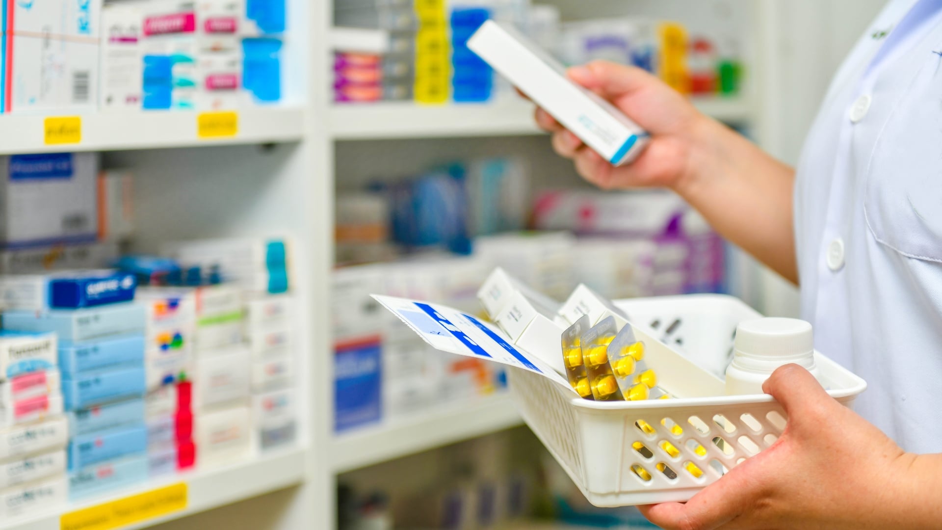 Pharmacist holding a basket of pills at the pharmacy
